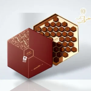علبة شوكولاتة ڤيلان كرمولايز الفاخرة سداسية الشكل باللون العنابي، مفتوحة وتكشف عن 42 قطعة شوكولاتة بلجيكية صغيرة بتصميم قرص العسل موضوعة داخل صينية ذهبية لامعة.